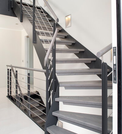 1/4 gewendelte HPL-Treppe , Handlauf und Stufen in der Holzart Buche grau gebeizt, Relinggeländer.