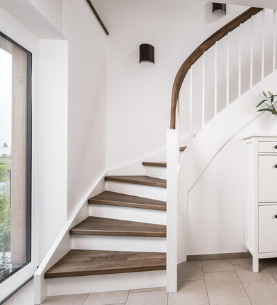 Eingestemmte, geschlossene Wangentreppe mit Stellwand, 1/4 gewendelt, Stufen und Handlauf (mit Krümmling) in der Holzart Buche mosaik schwarz geölt mit TBV Echtholz-Öl V-Black, Setzstufen, Pfosten und Stäbe in der Holzart Whitewood weiß endlackiert