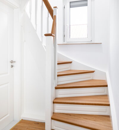 Geschlossene Wangentreppe mit Stellwand und eingefrästem Profil in die Setzstufen. Stufen und Handlauf in der Holzart Eiche farblos geölt.