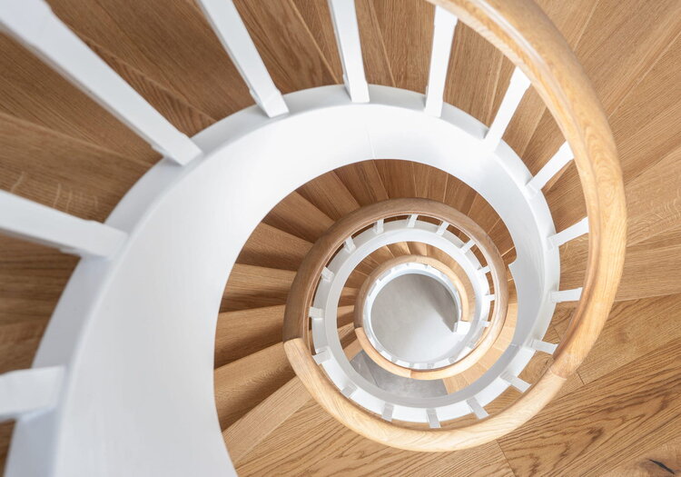 Geschlossene Wangentreppe über 4 Etagen; Wangen, Stäbe und Setzstufen weiß endlackiert; Stufen und Handlauf in der Holzart Eiche geölt. Treppe im Keller von unten mit Raumtrennung, um Raum unterhalb der Treppe zu nutzen.