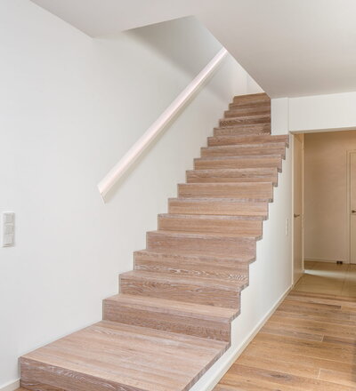 Stufen und Handlauf in der Holzart Akazie mosaik geölt, Wangen verkleidet, eingebautes Regalsystem unter der Treppe