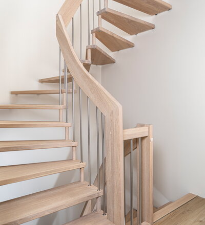 Halb gewendelte, freitragende Treppe in der Holzart Eiche weiß geölt mit Edelstahlstäben.