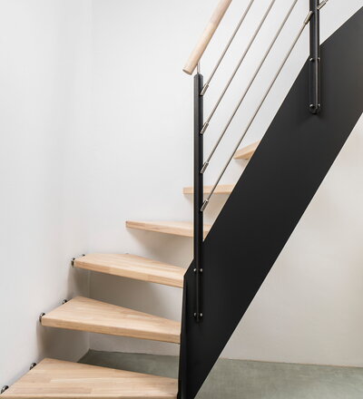 1/4 gewendelte HPL-Treppe, Sonder-Kombination: Stufen wandseitig gummigelagert eingebohrt und freiseitig mit einer HPL-Wange samt Geländer befestigt. Stufen und Handlauf in der Holzart Hevea mosaik mit TBV Echtholz-Öl Cotton White geölt