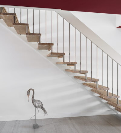 Gerade freitragende Treppe, Stufen in der Holzart Eiche mosaik weiß geölt, Geländerstäbe und Distanzrollen aus Edelstahl, Handlauf weiß endlackiert