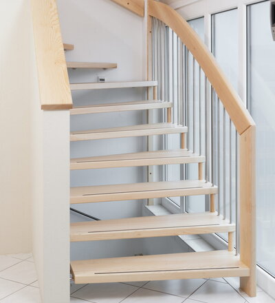 1/4 gewendelte freitragende Treppe, wandseitig gummigelagert, Holzart Esche mit Anti-Rutsch-Kante in der Stufenvorderkante, Edelstahlstäbe E16.