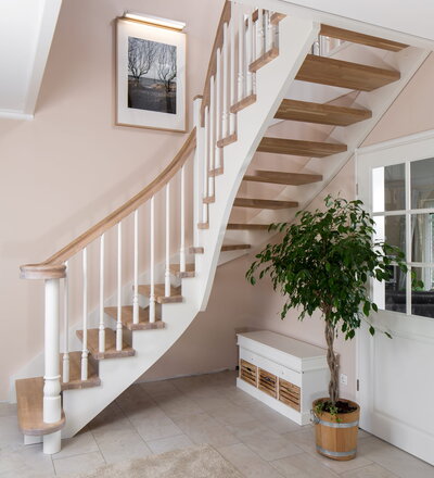 Wandseitig eingestemmte, freiseitig aufgesattelte Wangentreppe, Wangen und Stäbe weiß endlackiert, Stufen und Handlauf in der Holzart Eiche mosaik geölt Variante 1. Handlauf auslaufend in einen flachen Schneckenpfostenkopf.