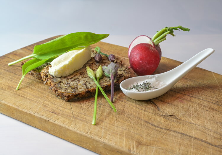Ein Ess-Brett mit einem Butterbrot, garniert mit Basilikum und Radieschen.