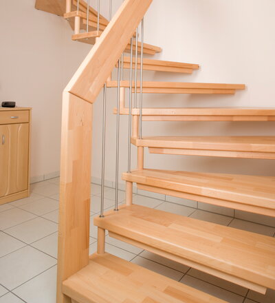 Viertel gewendelte freitragende Treppe in der Holzart Buche mosaik mit Edelstahlstäben und Distanzhaltern in der Holzart Buche mosaik.