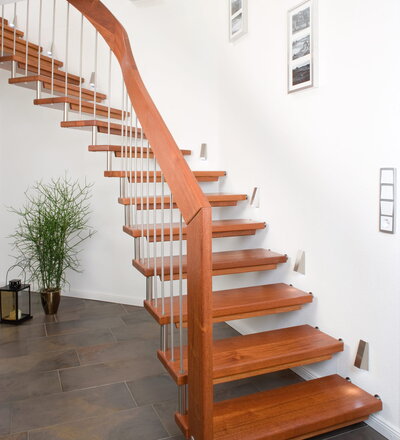 <p>1/4 gewendelte freitragende Treppe mit passender Mauerabdeckung, Distanzrollen und wandseitige Rosetten in Edelstahl; Holzart Merbau</p>