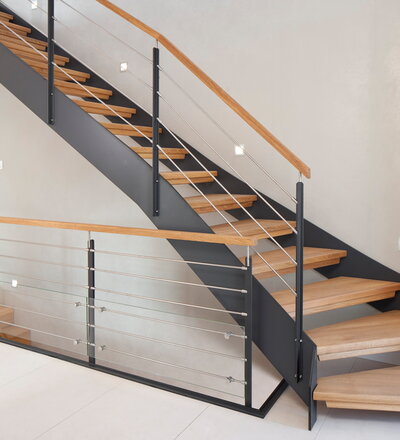 1/4 gewendelte HPL-Treppe mit Stufen und Handlauf in der Holzart Eiche geölt. Milano-Geländer mit zusätzlichem VSG-Glas.