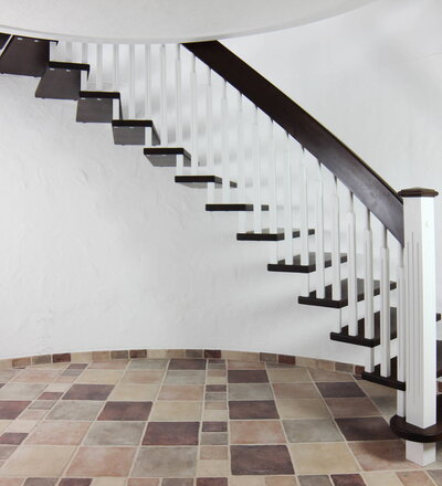 Gebogene freitragende Treppe über 2 Stockwerke, Stufen und Handlauf Holzart Buche gebeizt auf Wenge; Stäbe und Pfosten Holzart Whitewood weiß endlackiert; Handlauf- und Wangenkrümmling.