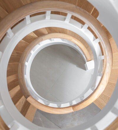 Geschlossene Wangentreppe über 4 Etagen; Wangen, Stäbe und Setzstufen weiß endlackiert; Stufen und Handlauf in der Holzart Eiche geölt. Treppe im Keller von unten mit Raumtrennung, um Raum unterhalb der Treppe zu nutzen.