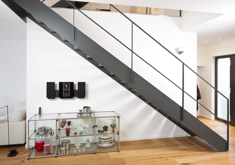 Gerade HPL-Treppe mit unsichtbar befestigten Holzstufe und einem aus filigranem Flachstahl hergestellten Geländer, welches im „Goldenen Schnitt“ angeordnet ist.