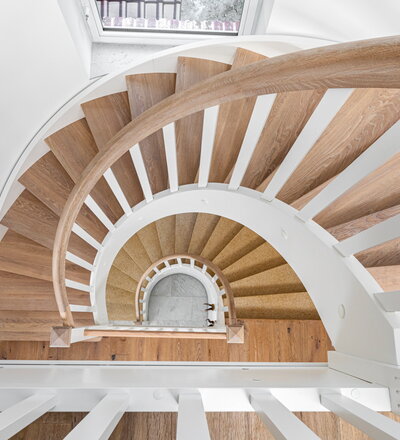 Beidseitig eingestemmte Wangentreppe, Stufen und Handlauf in der Holzart Eiche „invisible“ geölt, Wangen, Stäbe und Pfosten weiß endlackiert.