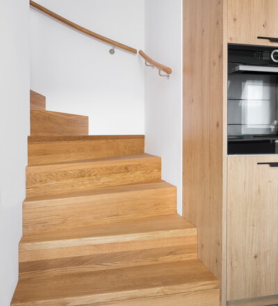 Aufgesattelte Wangentreppe in Faltwerkoptik zwischen zwei Wänden in der Holzart Eiche Pure (farblos) geölt mit TBV Echtholz-Öl