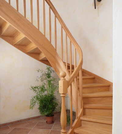 Beidseitig eingestemmte, geschlossene Wangentreppe; Holzart Buche geölt, gedrechselter Pfosten PF1, gedrechselte Stäbe HA1 und Handlaufkrümmling, gebogenes Brüstungsgeländer.