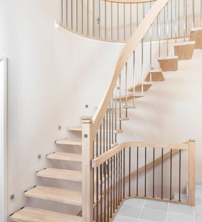 1/4 gewendelte freitragende Treppe mit Handlaufkrümmling in der Holzart Hevea mosaik weiß geölt. Stäbe Q16 aus Edelstahl.