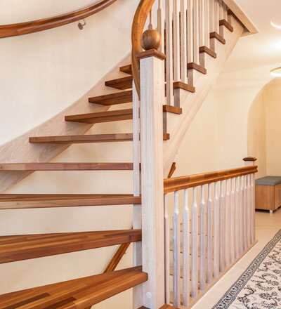 Wandseitig eingestemmte, freiseitig aufgesattelte Wangentreppe, Stufen und Handlauf in der Holzart Akazie farblos geölt, Wangen, Stäbe und Pfosten und der Holzart Eiche weiß geölt.